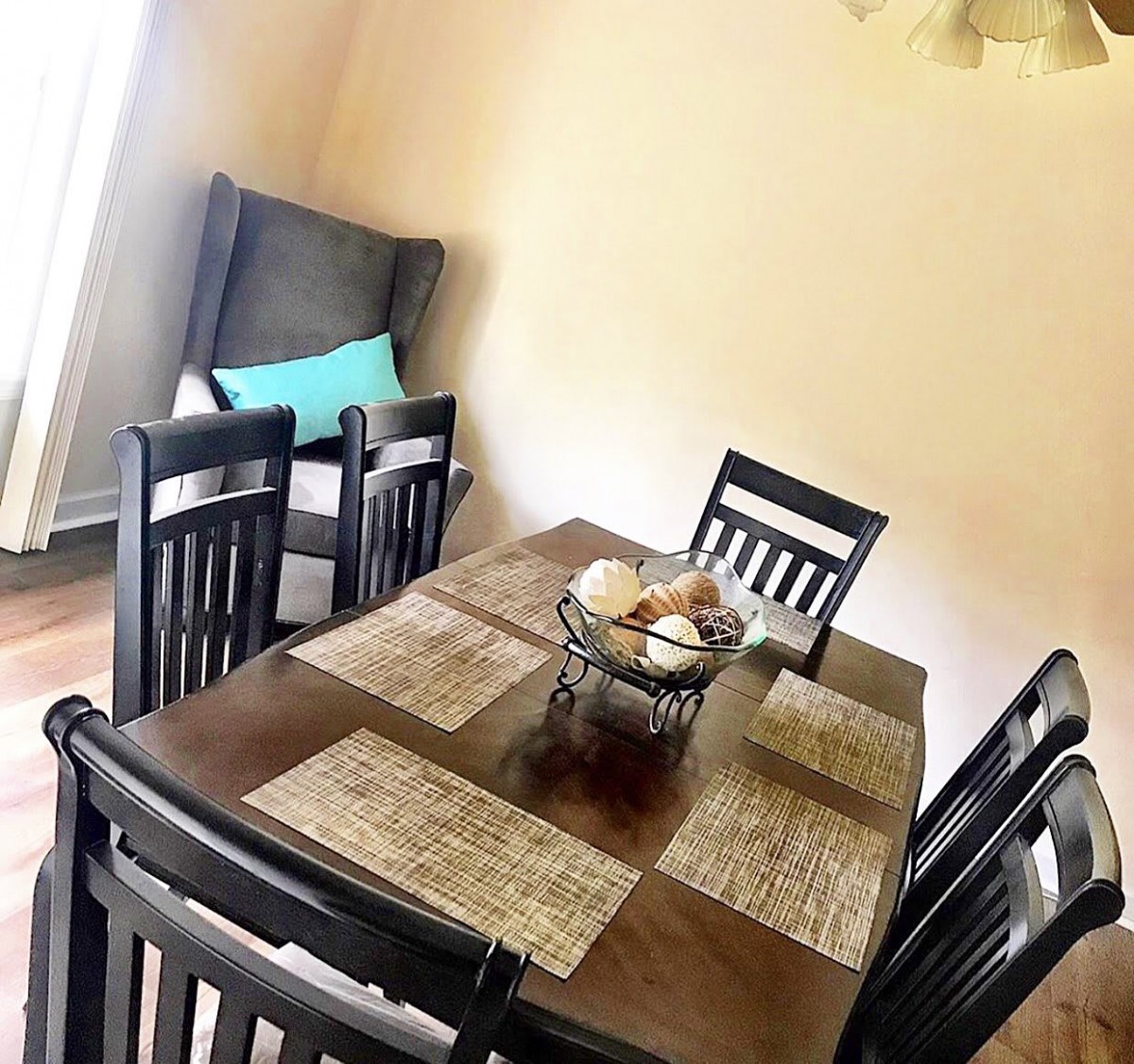 A cozy dining room with a wooden table set for a meal, featuring neatly arranged placemats and comfortable chairs.