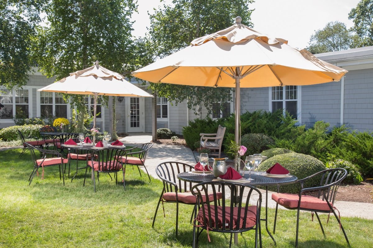 A charming outdoor seating area with tables, chairs, and umbrellas in a landscaped garden.