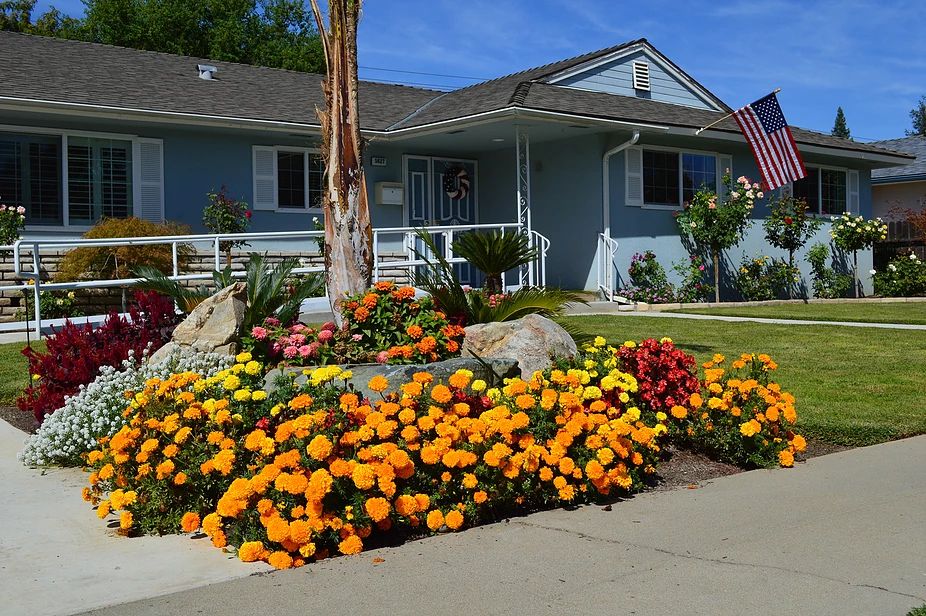 A charming house with a beautifully landscaped front yard filled with vibrant flowers.