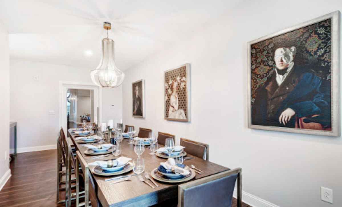 A modern dining room with an elegantly set table and contemporary artwork on the walls.