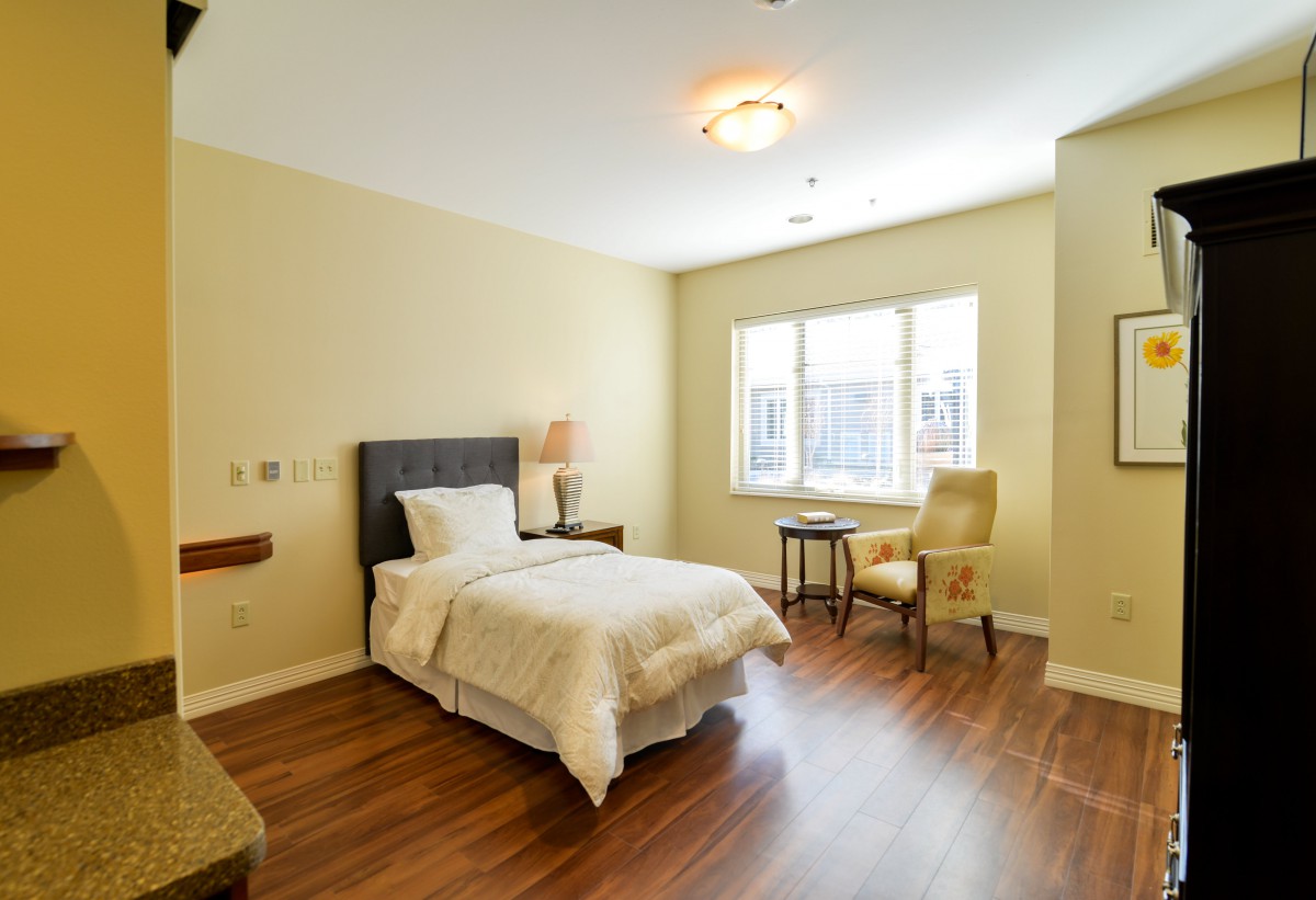 A bright and cozy bedroom with a single bed, chair, and window.