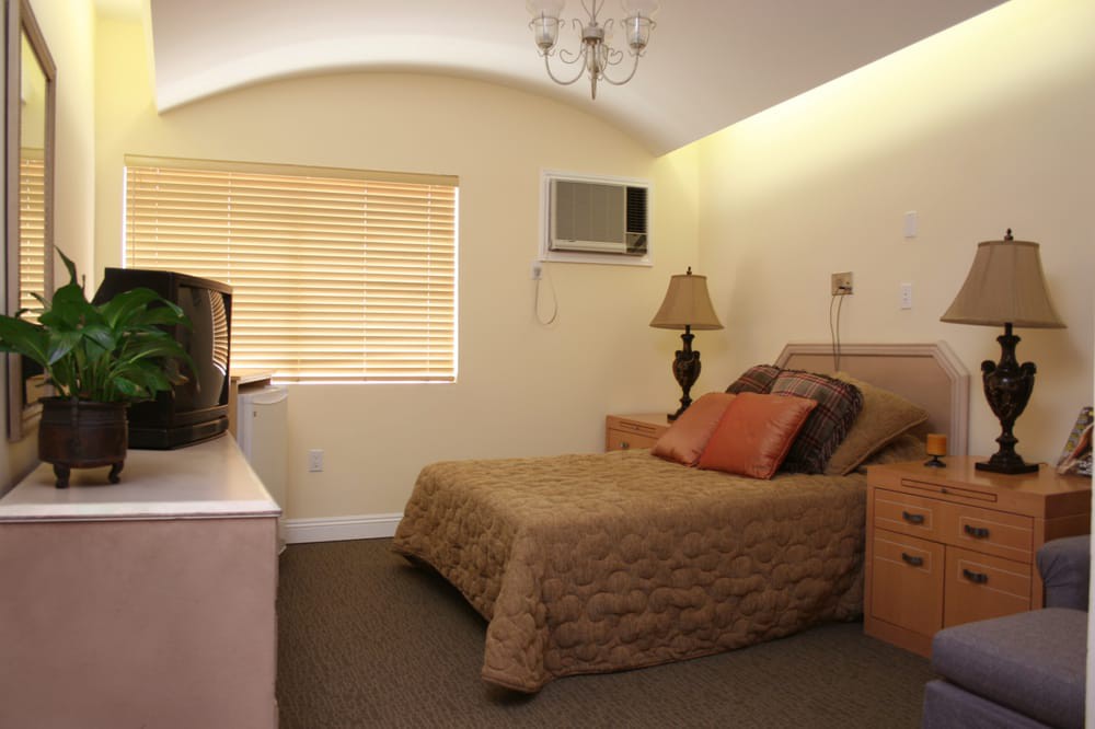 A cozy hotel bedroom with a bed, TV, and lamp.