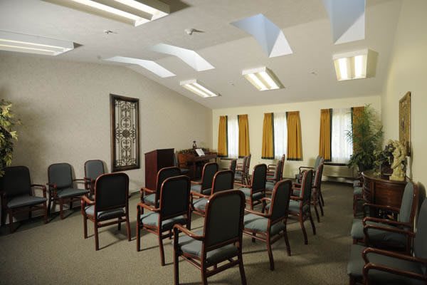 A small conference room with arranged chairs and a piano near the windows.