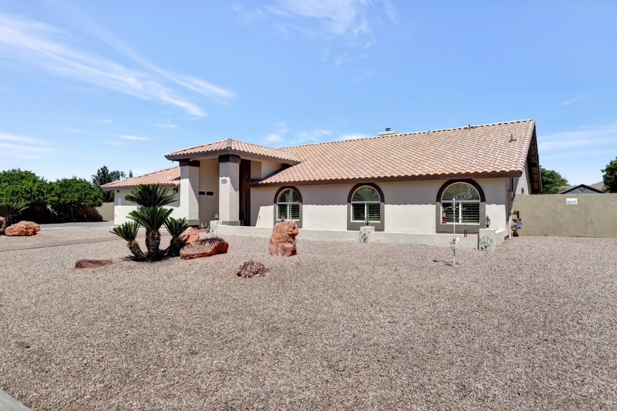 A single-story house with a desert landscape and a clear blue sky.