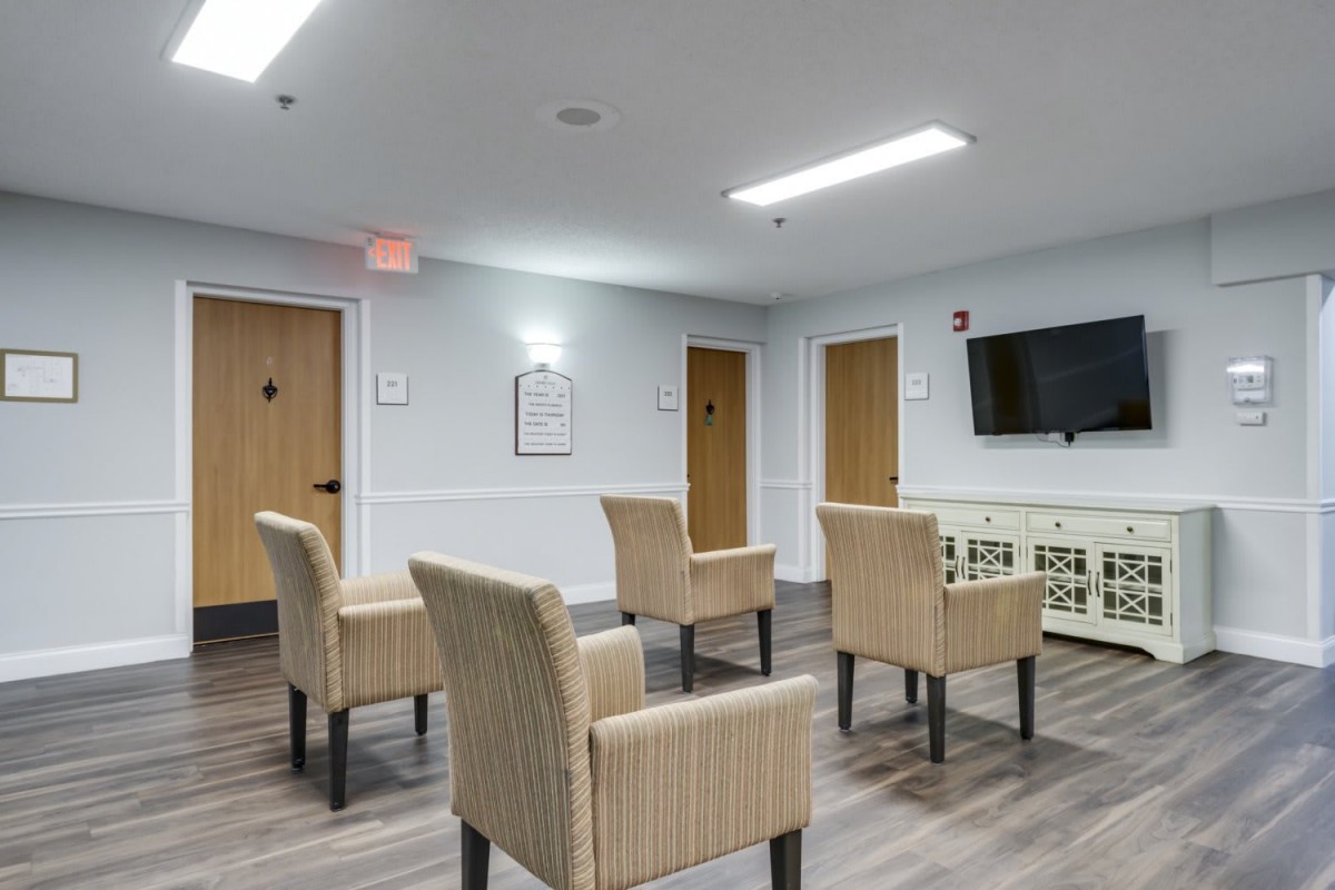 A modern waiting room with arranged chairs and a wall-mounted television.