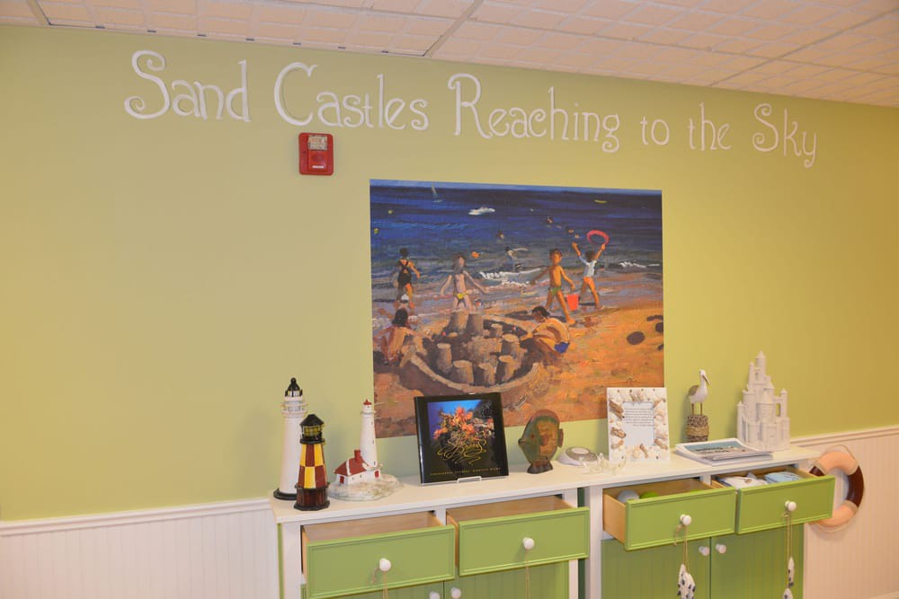 A room interior featuring a sand castle and beach-themed decor with green walls and shelving.