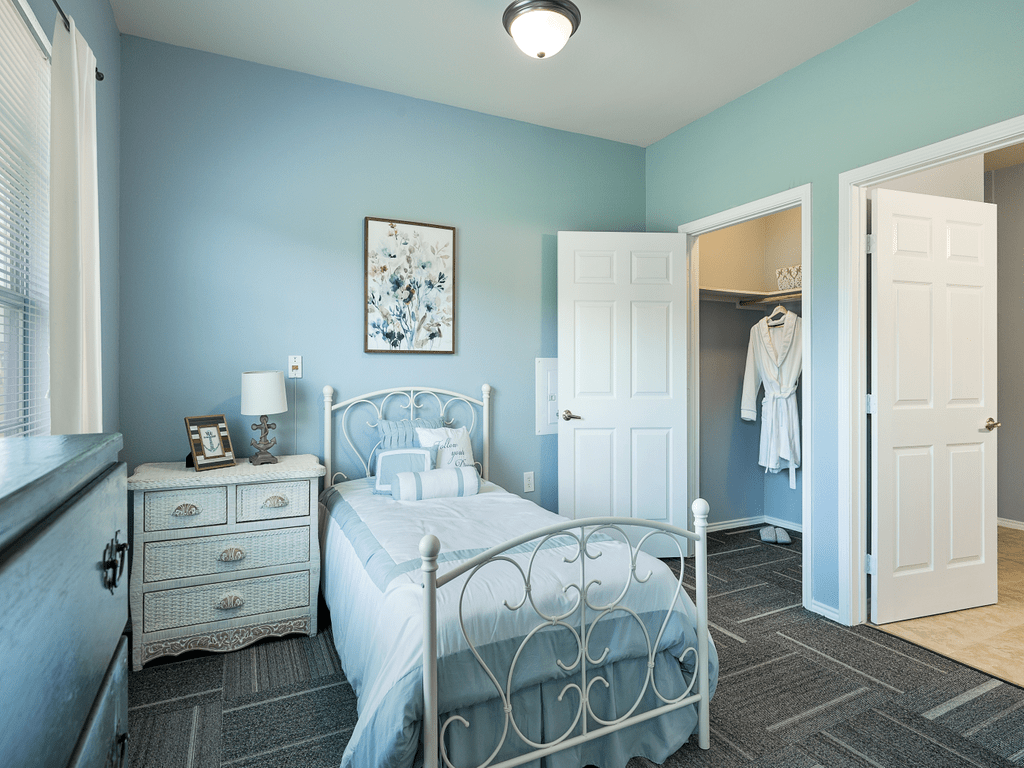 A cozy bedroom with blue walls, featuring a single bed and a nightstand.