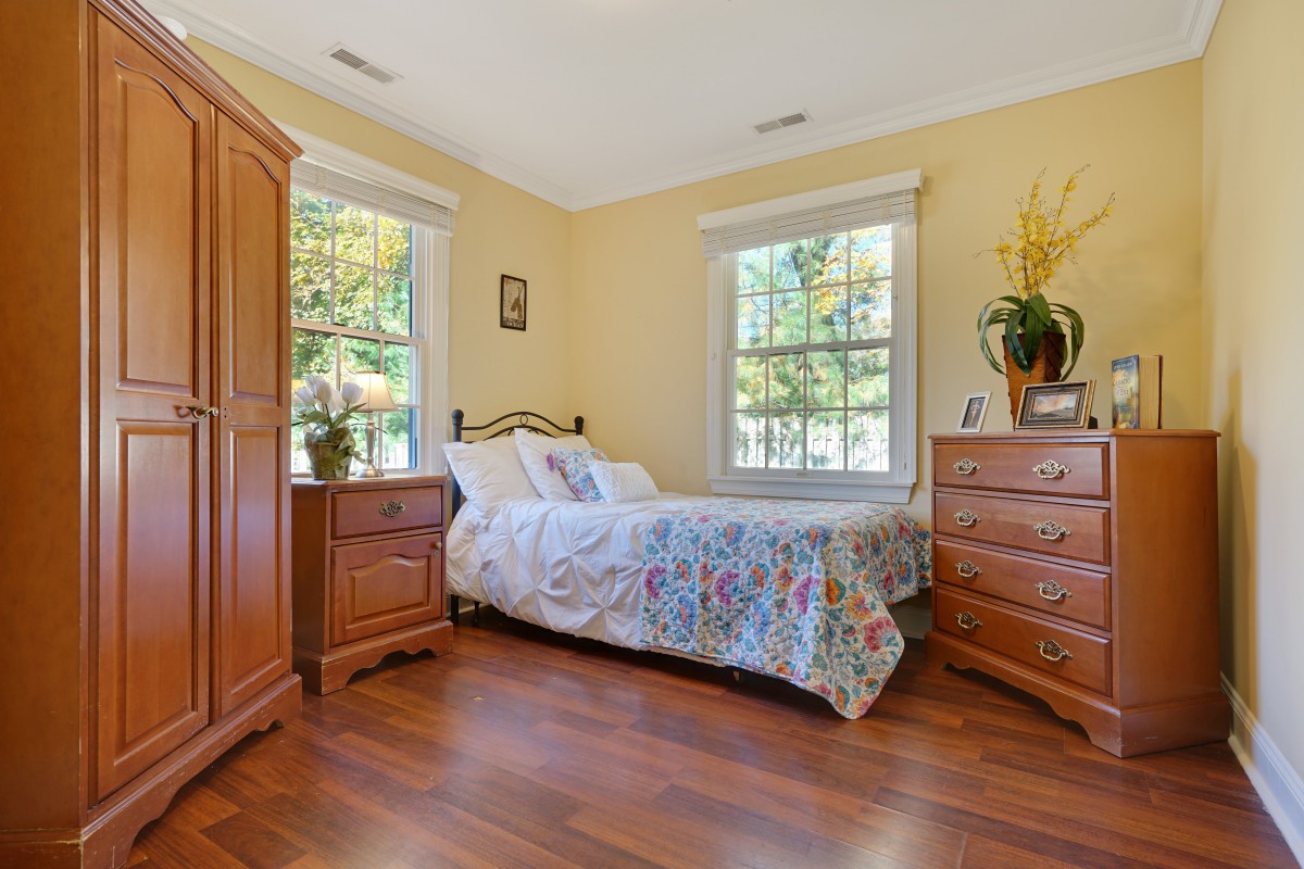A cozy bedroom with wooden furniture and bright natural lighting.