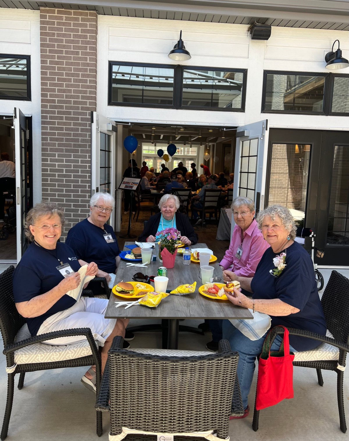 A group of seniors enjoying a meal together at an outdoor restaurant setting.