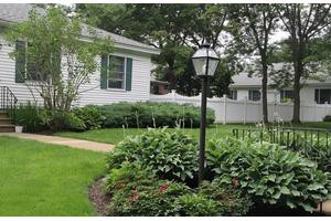 A quaint residential house with a lush garden and a classic lamp post.