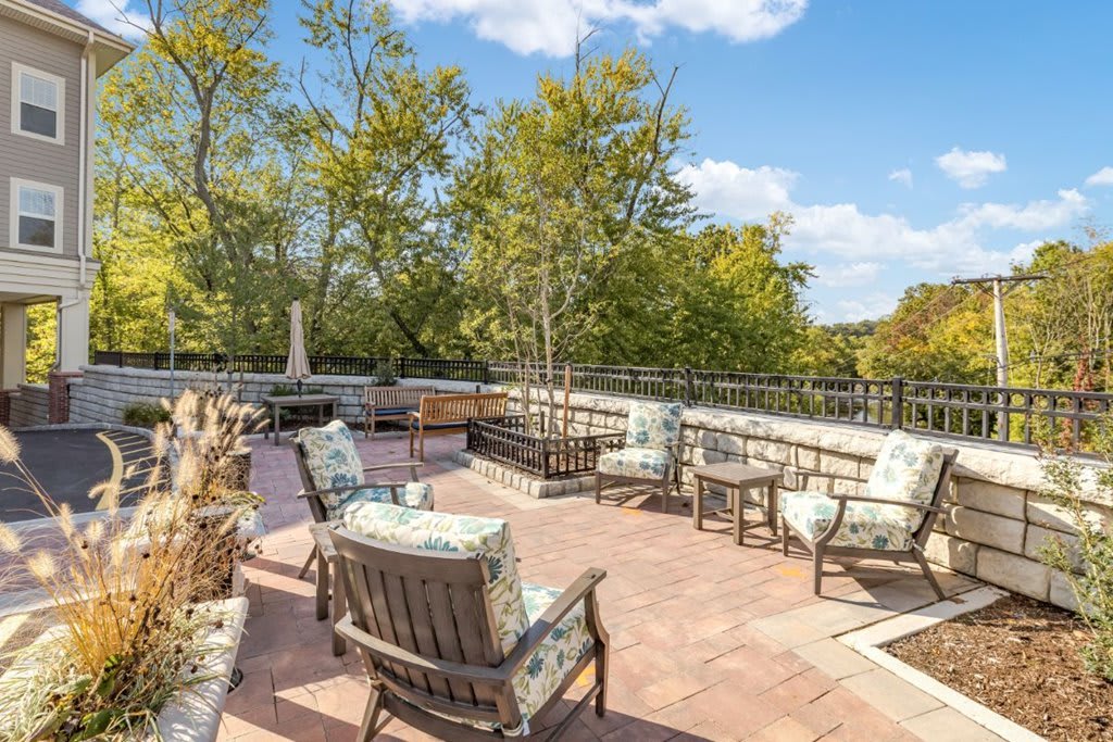 A spacious outdoor patio with comfortable seating, surrounded by trees and under a clear blue sky.