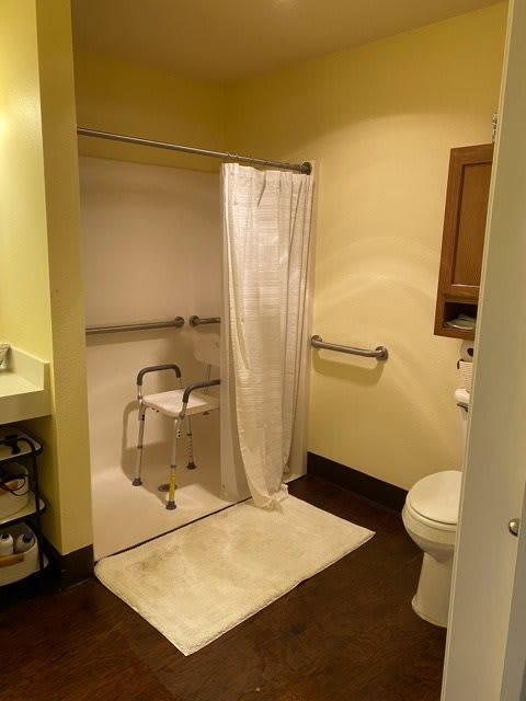 An accessible bathroom featuring a shower with grab bars and a shower chair.