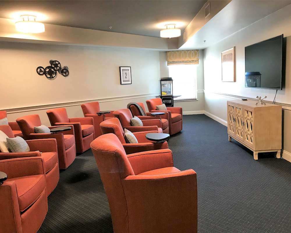 A cozy theater room with comfortable seating and a large television.