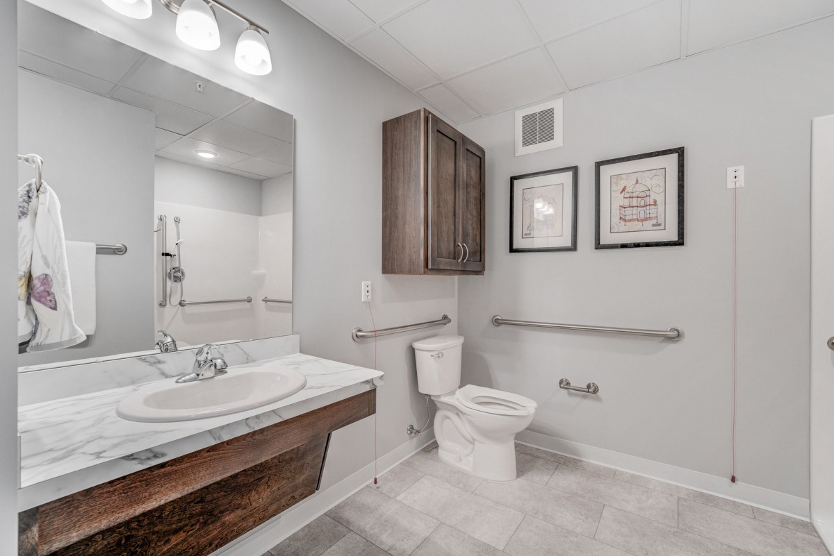 A modern bathroom with a sink, toilet, and decorative wall art.