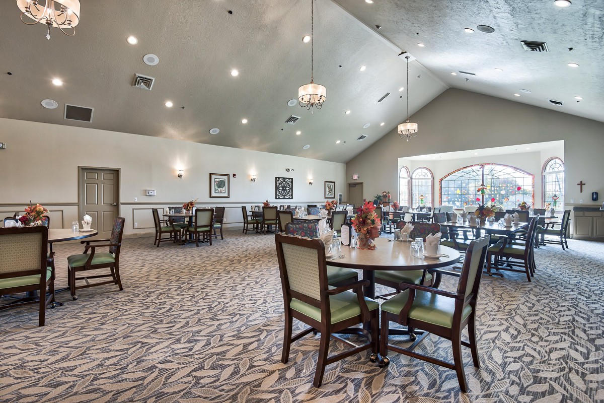 Spacious dining area with elegantly arranged tables and chairs, highlighted by modern lighting fixtures.