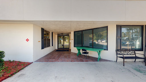 An entrance featuring large glass doors and a distinct green table, welcoming visitors.