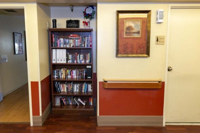 A cozy corner featuring a bookshelf filled with books and DVDs, alongside framed wall art.
