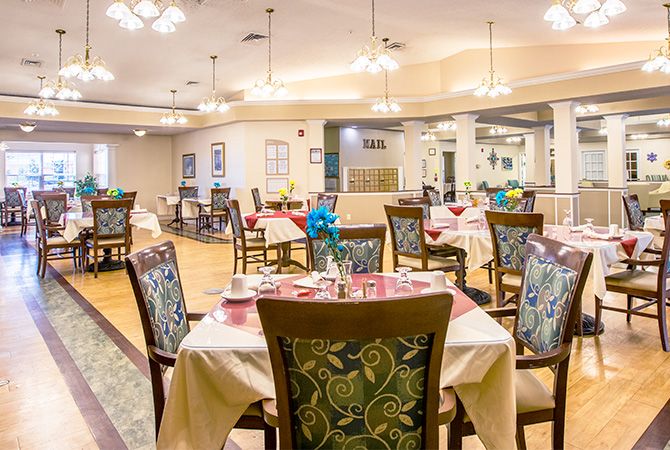 A well-decorated dining area with neatly arranged tables and chairs, illuminated by elegant lighting.