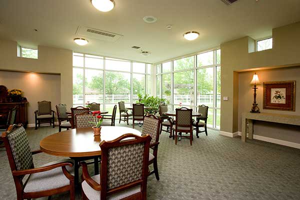 A well-lit dining area featuring several tables and chairs, with large windows allowing natural light to fill the room.