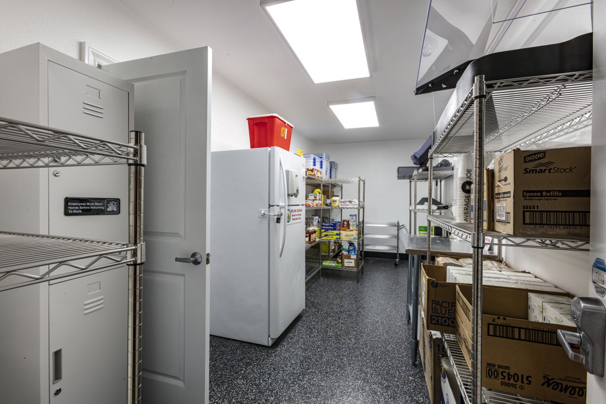 A well-organized industrial storage room with shelving and a refrigerator.