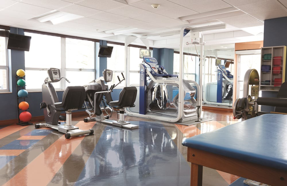 A modern gym with various exercise equipment including treadmills and stationary bikes.