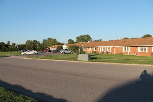A view of a quiet residential area with neatly arranged buildings and parked cars under a clear blue sky.