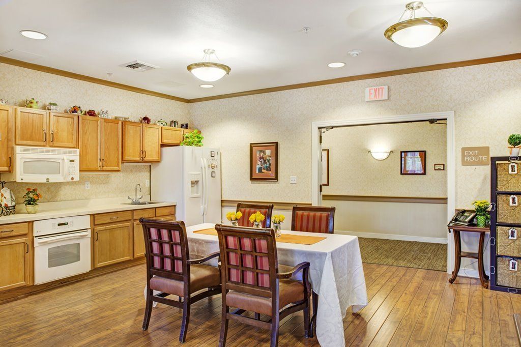 A well-lit dining area with a wooden table and chairs, adjacent to a kitchen space.