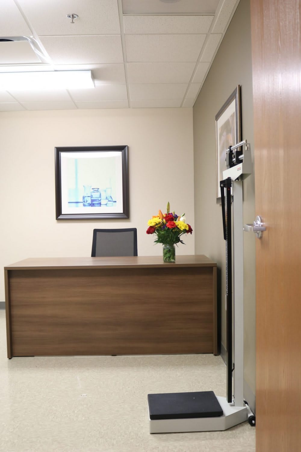 A tidy office with a wooden desk, a chair, and a bouquet of flowers.