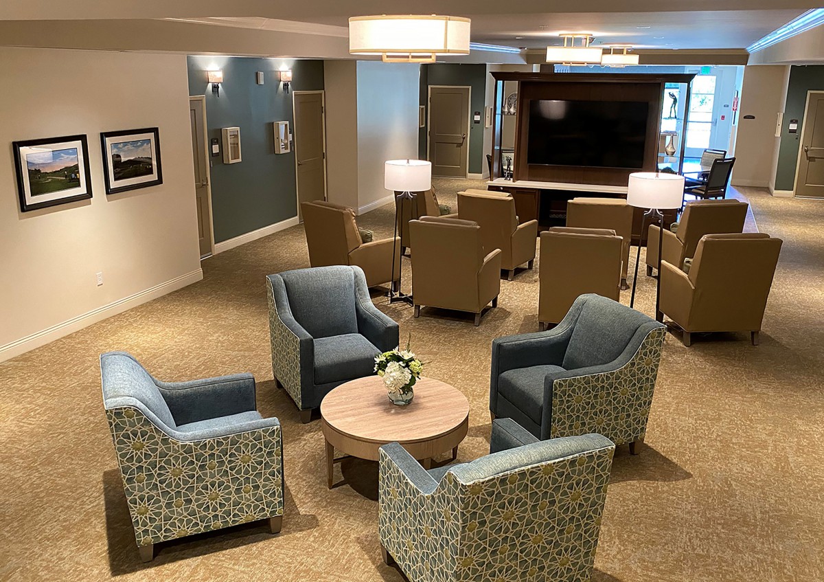 A modern lobby seating area with comfortable chairs, a table, and a television.