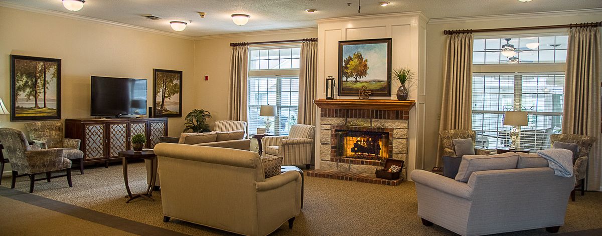 A cozy living room featuring a warm fireplace, comfortable seating, and a large window.