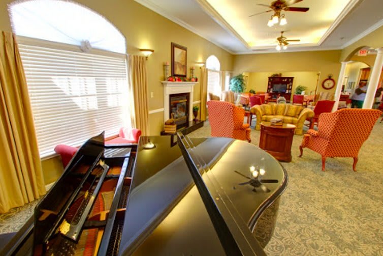 A cozy living room featuring a grand piano, fireplace, and comfortable seating area.
