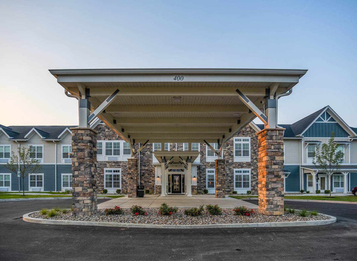 Front view of a residential building with a covered entrance supported by stone pillars.