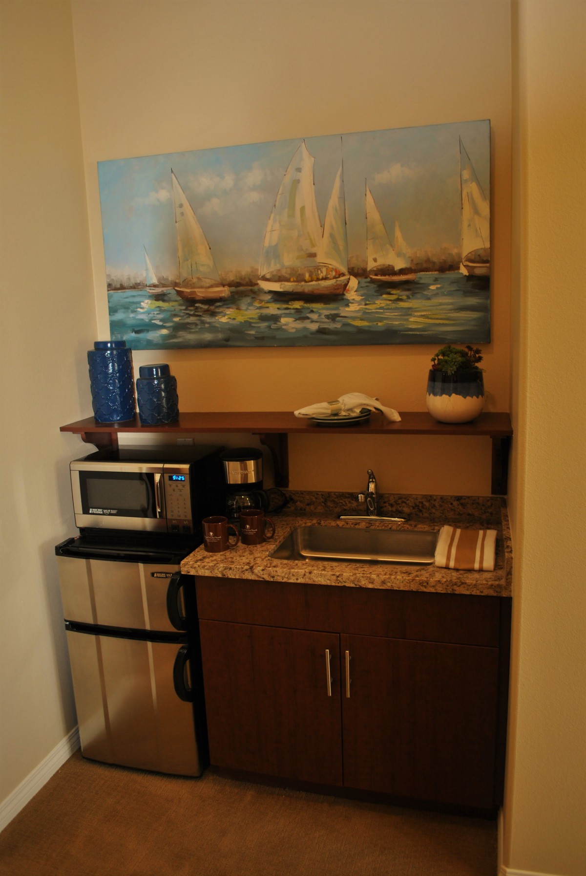 A compact kitchenette with a microwave, mini fridge, and nautical-themed decor.