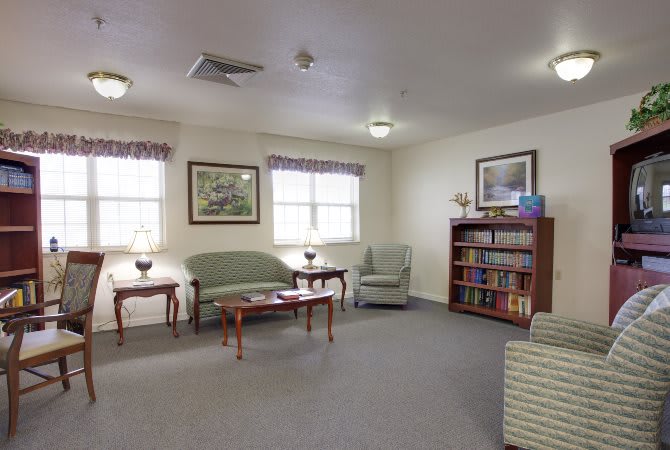 A cozy living room with a sofa, armchairs, and a bookshelf.