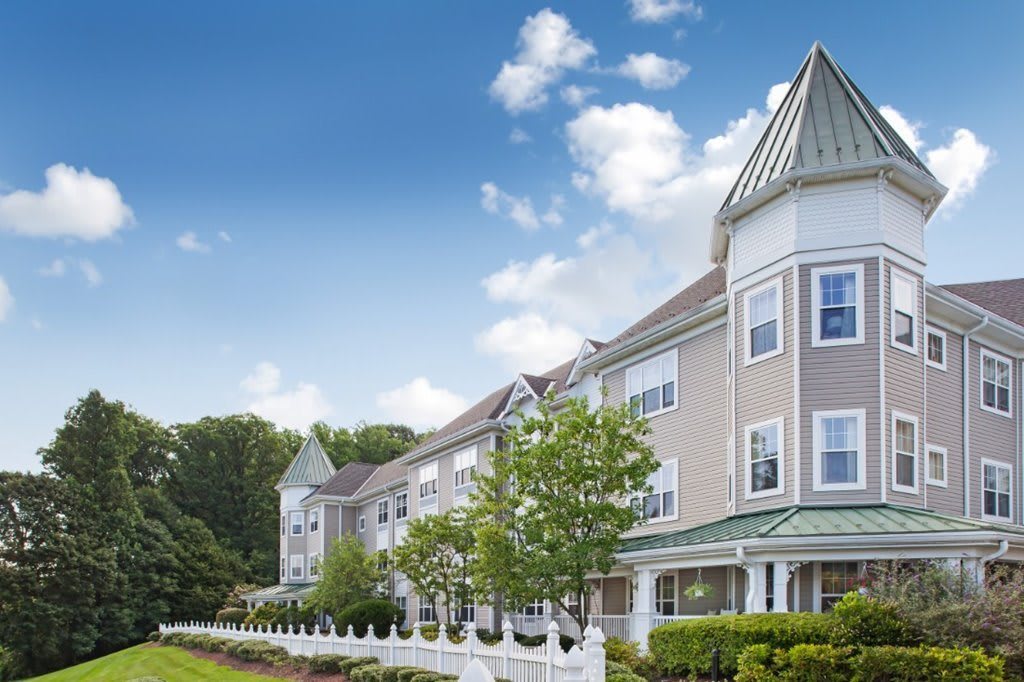 A picturesque view of a residential building with a blue sky and scattered clouds.