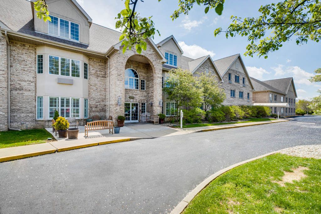A large building with a welcoming entrance, surrounded by well-maintained landscaping and trees on a sunny day.