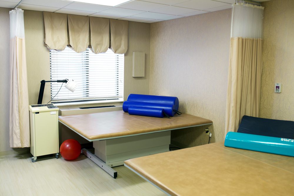 A therapy room with rehabilitation equipment, featuring therapy tables and exercise balls.