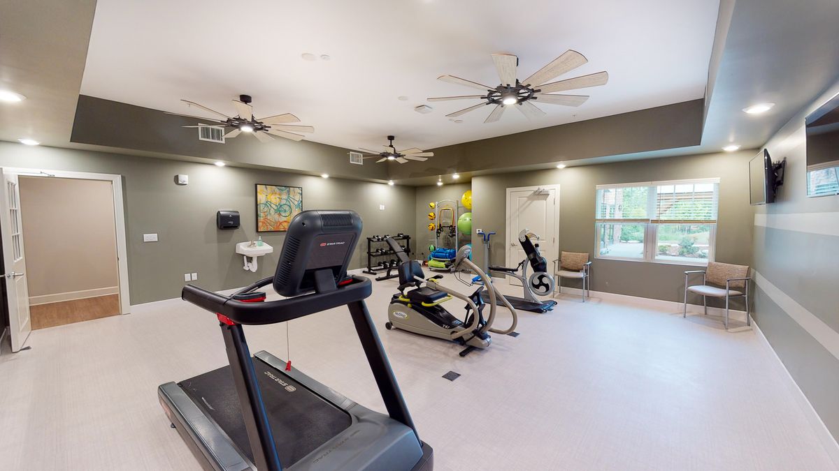 A modern gym with various exercise machines, including a treadmill and stationary bikes.