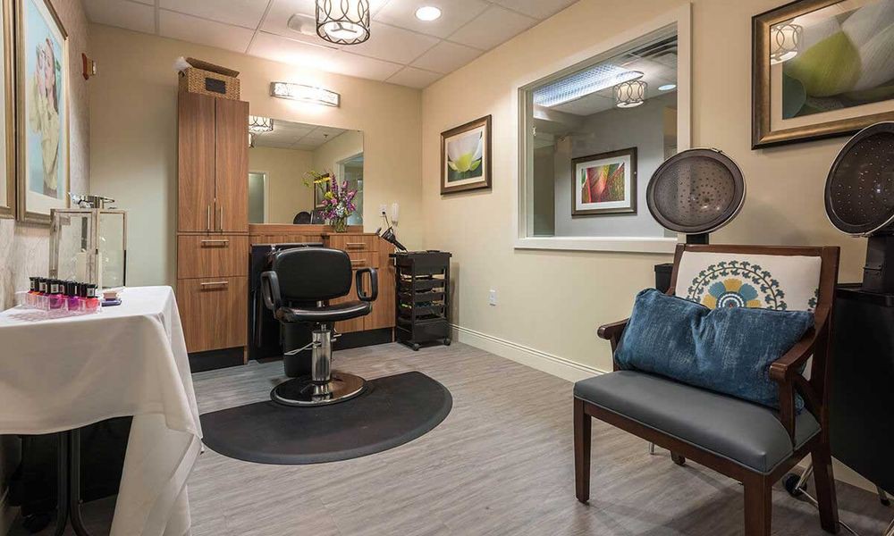 A cozy hair salon with a styling chair, waiting area, and artwork on the walls.