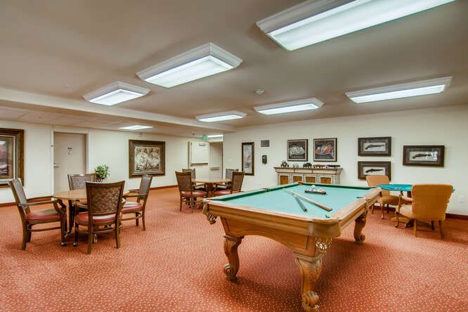 A well-lit billiards room with a pool table and seating area.