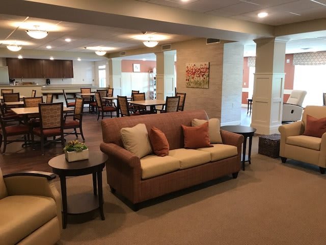 A cozy living room with a sofa and tables, leading to a dining area.