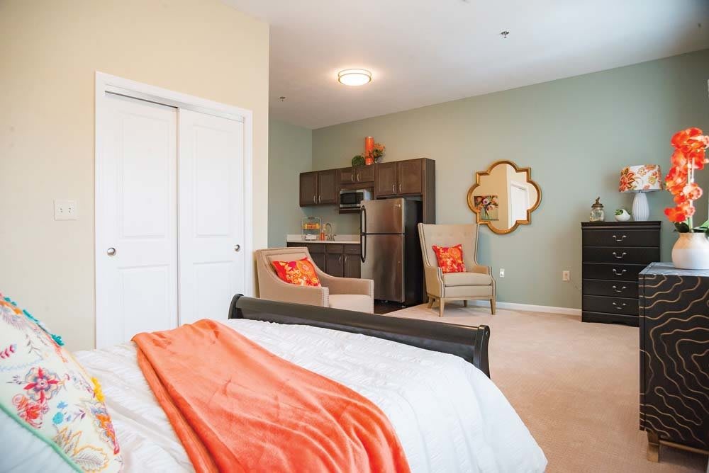 A modern, cozy bedroom with a kitchenette featuring stylish furniture and warm decor.