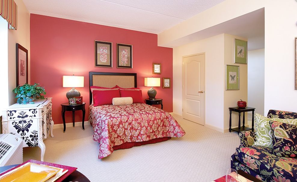 Cozy bedroom featuring a red accent wall and artistic decor.