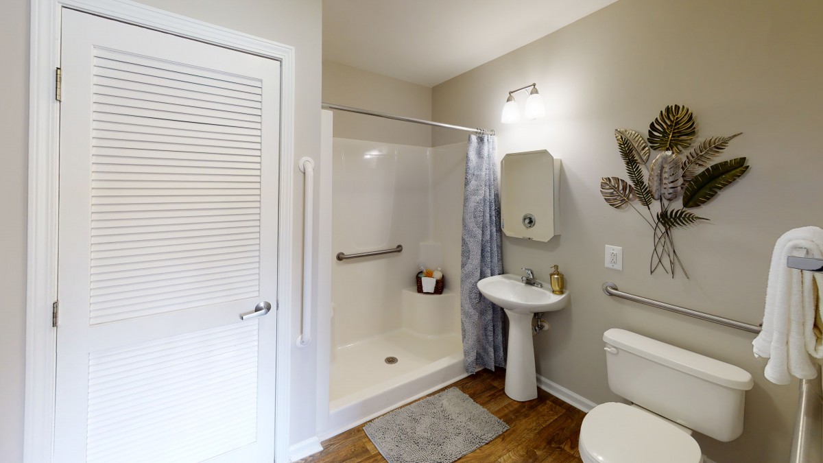A modern bathroom with a shower, sink, and toilet.