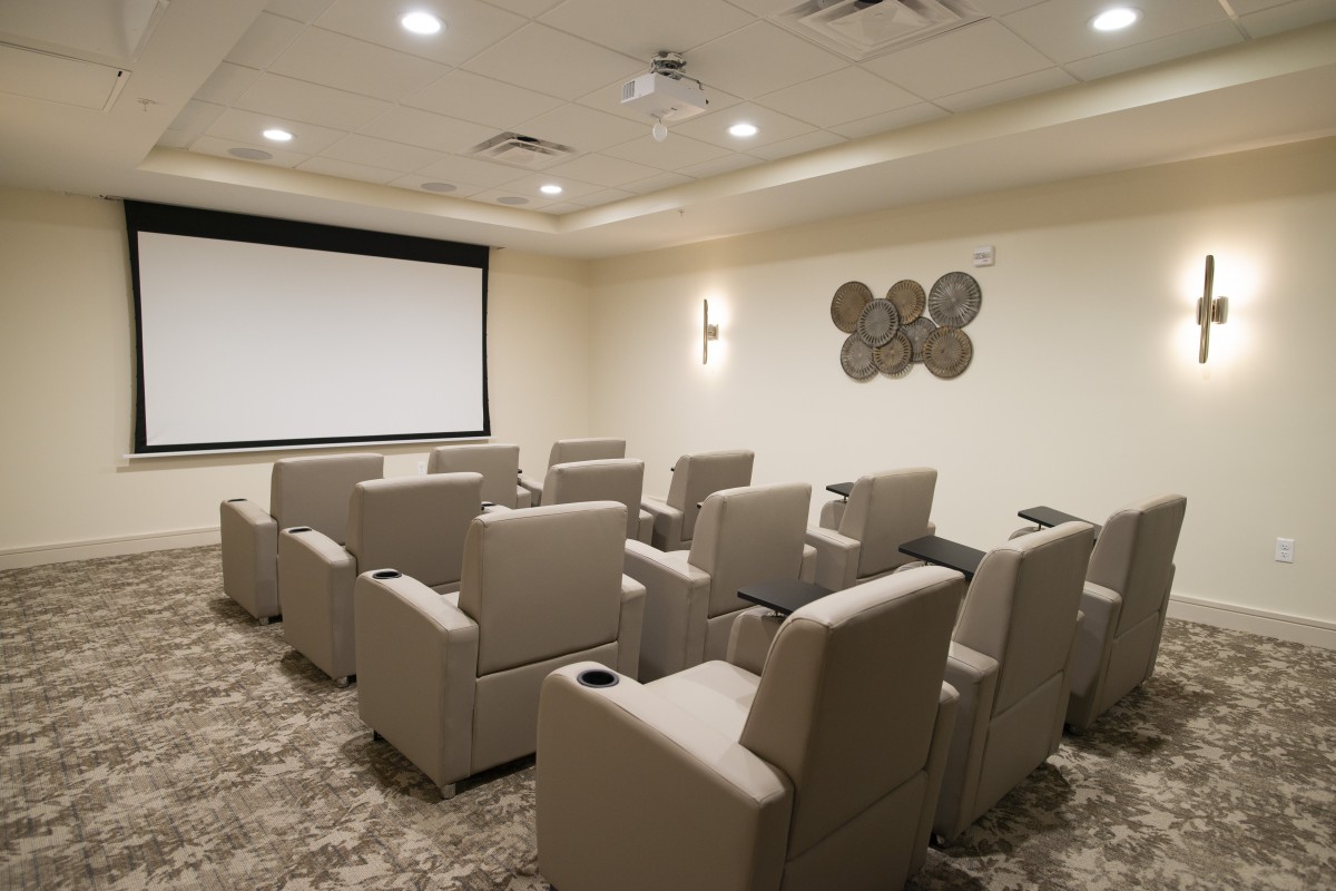 A modern home theater room with plush seating and a large screen, designed for a luxurious viewing experience.