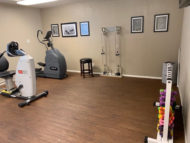 A neatly organized exercise room with gym equipment and wall decor.