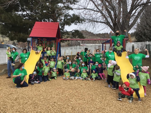 A cheerful group of children in green shirts enjoying a fun day at the playground.