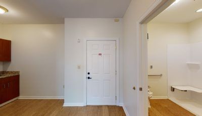 An interior view of a room with a white door and wooden flooring.