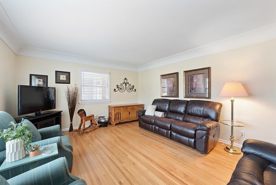 A cozy living room with a leather couch, hardwood flooring, and decorative elements.