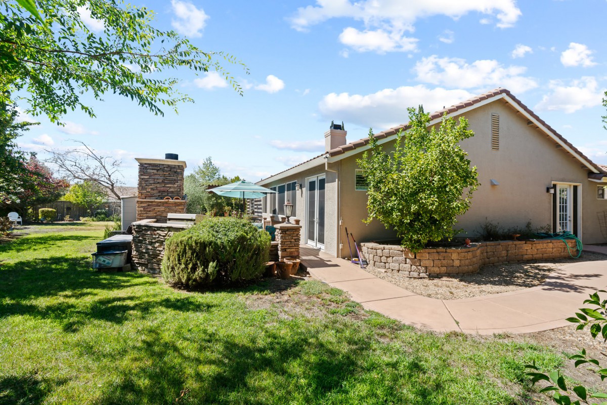 A backyard with a patio area, outdoor furniture, and a well-maintained lawn on a sunny day.